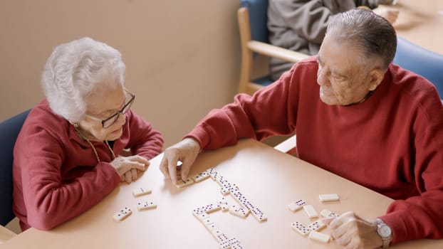 Senior man playing dominoes with old friend in a geriatric