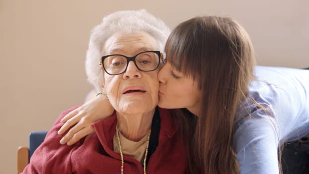 Cute granddaughter embracing and kissing her grandmother in a geriatric