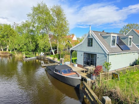 A peaceful scene of a boat calmly sitting in the tranquil water, reflecting the serene beauty of the surroundings. wooden facades and old houses in Broek in Waterland in the Netherlands