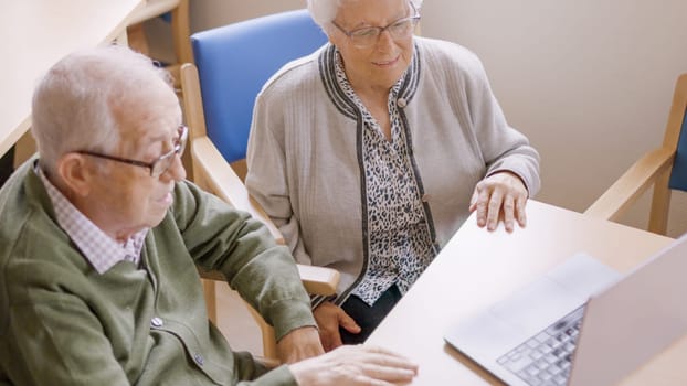 Grandparents sitting using laptop during a video call