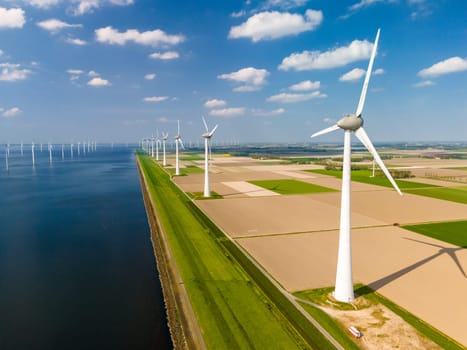 A mesmerizing landscape of wind turbines gracefully spinning in a wind farm by a serene body of water, showcasing sustainable energy production. Noordoostpolder Netherlands