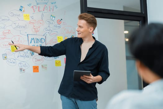 Professional male leader presents start up project by using mind map, colorful sticky notes and business statistic graph with confident while investor listening at business meeting. Immaculate.