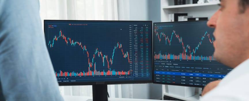Stock exchange traders discussing digital currency on panorama view in market online focusing on real time dynamic data with two screens, analyzing increased trend investment at workplace. Sellable.