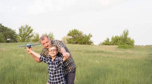 Father and son having fun in the field playing with an airplane. Father's day concept.