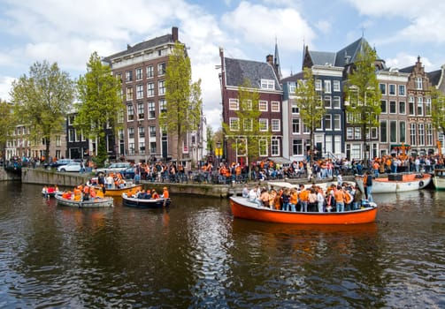 Amsterdam, Netherlands - April 27, 2024: Local dutch people celebrating kingsday on the canals in Amsterdam in the Netherlands