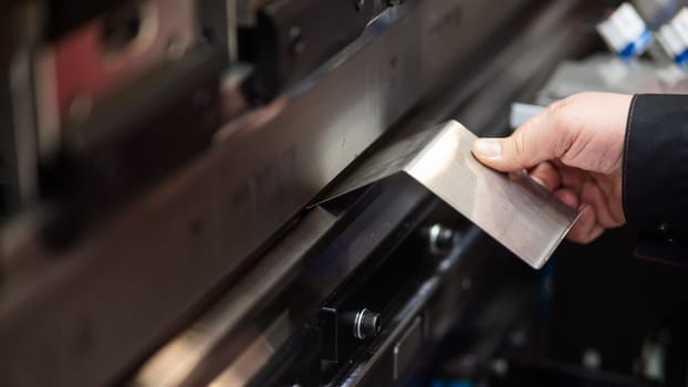 A master bends metal sheets on a machine. Hydraulic Press