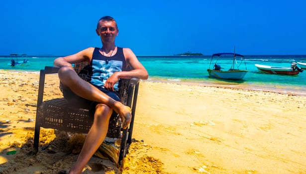 Super happy man in the water and on a paradisiacal tropical beach on Rasdhoo island in Rasdhoo Atoll Maldives.