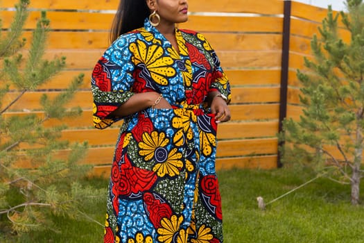 Summer portrait of beautiful african american woman in red casual wear standing on backyard. Suburban lifestyle and chilling on weekend in countryside concept