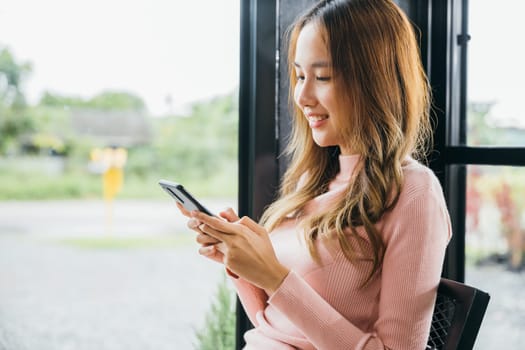 Young woman typing text message on smart phone device apps in cafe, beautiful female holding cellphone in hands and chatting social network with friends or reading email, mobile phone