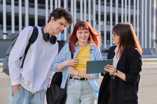 Middle aged business woman agent mentoring teacher social worker working with college university students using digital tablet outdoor