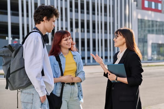 Middle aged business woman agent mentoring teacher social worker working with college university students using digital tablet outdoor