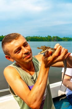 Man tourist with baby crocodile alligator in his hands at Bantota Ganga river in Bentota Beach Galle District Southern Province Sri Lanka.