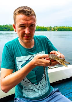 Man tourist with baby crocodile alligator in his hands at Bantota Ganga river in Bentota Beach Galle District Southern Province Sri Lanka.