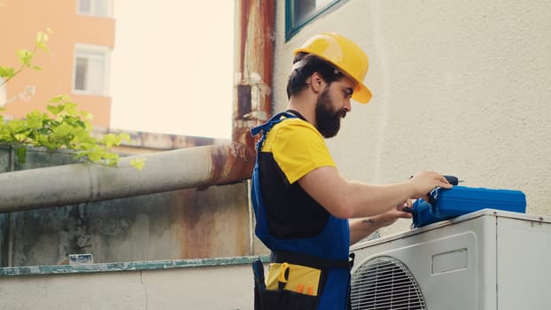 Skilled mechanic commissioned by client, preparing equipment for annual air conditioner maintenance. Technician unpacking toolkit with professional gear needed to patch up damaged draining lines