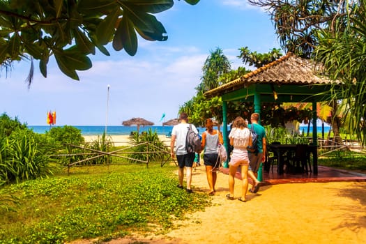 Beautiful beach with tropical nature sand water waves people fun parasols and sun loungers in Bentota Beach on Sri Lanka island.