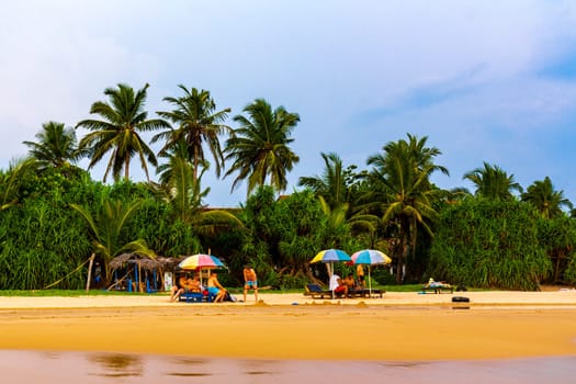 Beautiful beach with tropical nature sand water waves people fun parasols and sun loungers in Bentota Beach on Sri Lanka island.