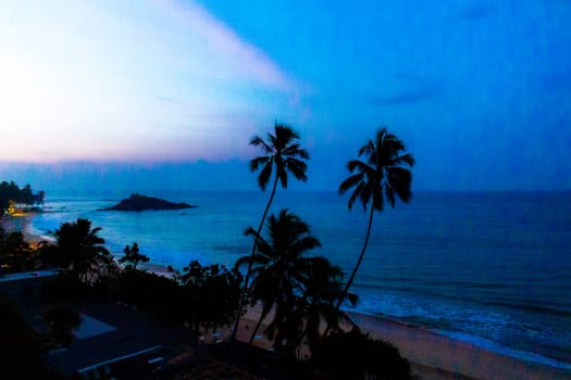 Beautiful golden colorful sunset sunrise at paradise tropical beach with palm trees waves and sea water view in Mirissa Beach Southern Province Sri Lanka.