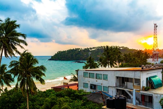 Beautiful golden colorful sunset sunrise at paradise tropical beach with palm trees waves and sea water view in Mirissa Beach Southern Province Sri Lanka.