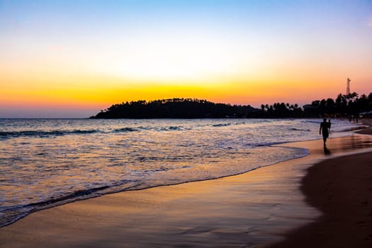 Beautiful golden colorful sunset sunrise at paradise tropical beach with palm trees waves and sea water view in Mirissa Beach Southern Province Sri Lanka.