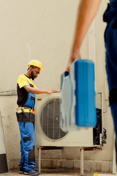 Master serviceman arriving on location to help apprentice worker fix unfunctional compressor in faulty hvac system. Experts coworkers contracted to prevent internal parts breakdowns