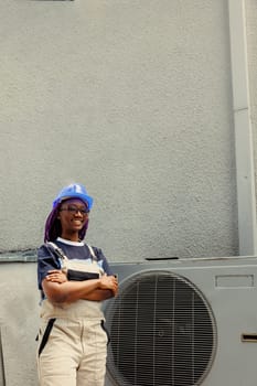Portrait of smiling skilled expert proud of work done, standing in front of refurbished air conditioner. Proficient worker hired by business owner happy with fast maintenance of hvac system parts
