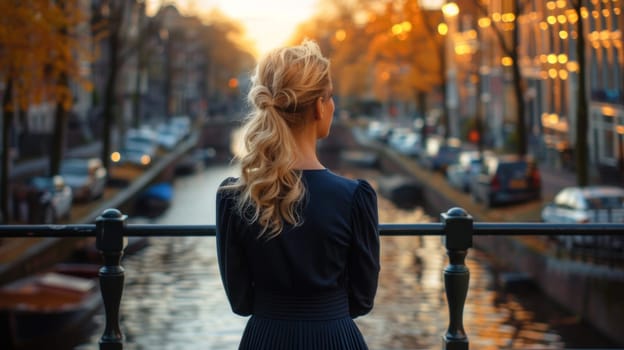 A woman in a blue dress stands on a bridge overlooking a canal.