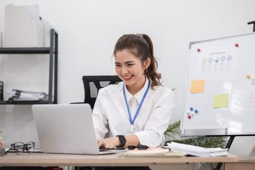 Beautiful determined business woman working using laptop recording data in modern office.