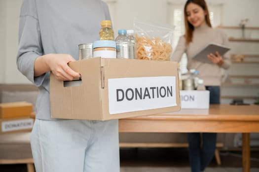 A beautiful female volunteer carries a donation box with canned food and food to donate to the Nothi Foundation..