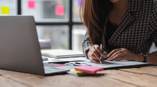 Close-up view of Asian businesswoman working online and planning financial calculation data working from home. Businesswoman and business planner concept.