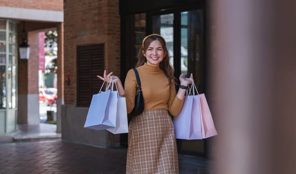 A woman is walking down a street with shopping bags in her hand.