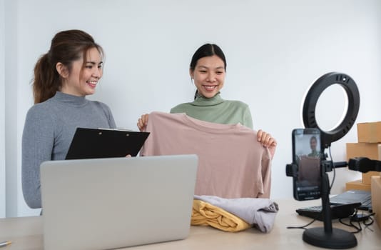 Two beautiful online sellers Business operators selling products online They are helping each other sell and teach trade via video streaming in a room