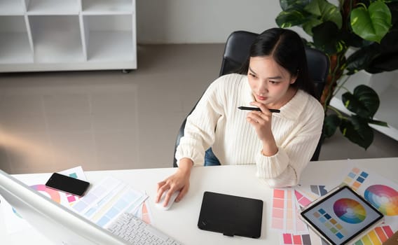 Top view of female designer working in graphic design using computer Sit and choose colors and work intently in your office..