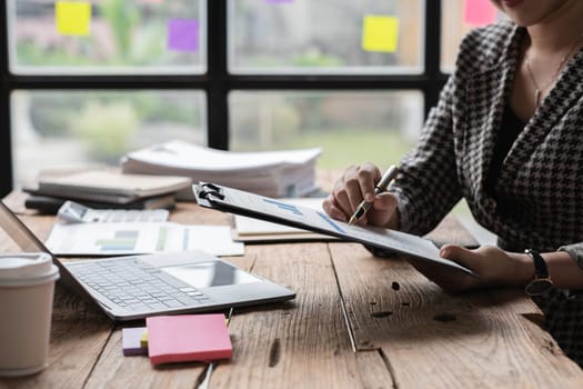 Close-up view of Asian businesswoman working online and planning financial calculation data working from home. Businesswoman and business planner concept.