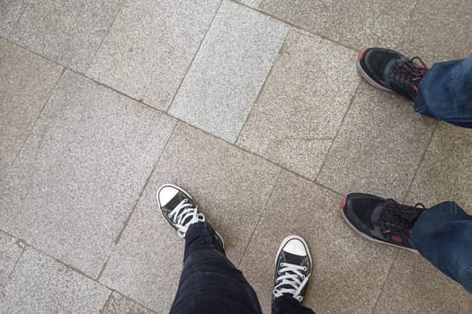 Men's and women's legs on paving slabs, copy space