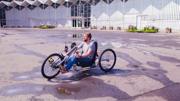 Happy young disable man is sitting in hand bike.