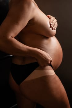 Pregnant woman pulls back her panties showing instant tan. Vertical photo