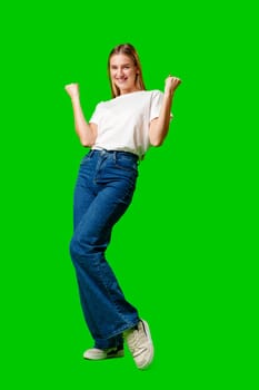 Happy Young Woman Raising Fists against green background in studio
