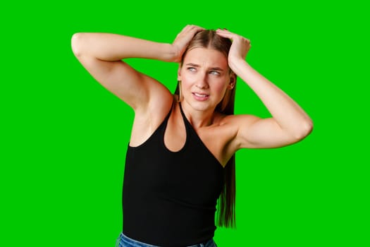 Young Woman Holding Hands Up to Head against green background in studio