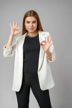 Confident Young Woman in Business Attire Giving Ok Sign in Studio Setting close up