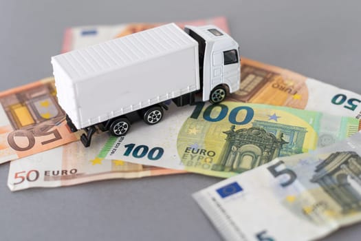 White toy truck lie on dollars, space for text. High quality photo