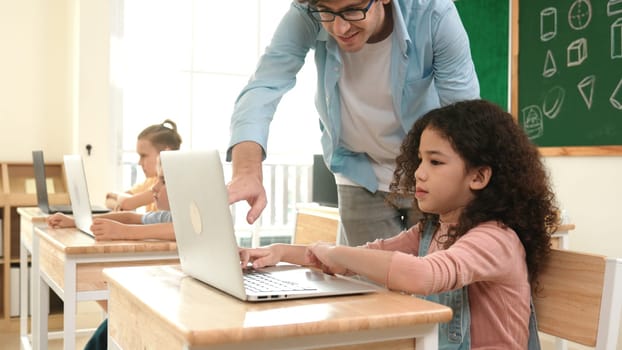 American girl learning about coding engineering prompt while diverse students sitting at STEM technology class. Multicultural children working on laptop to generated AI by using software. Pedagogy.