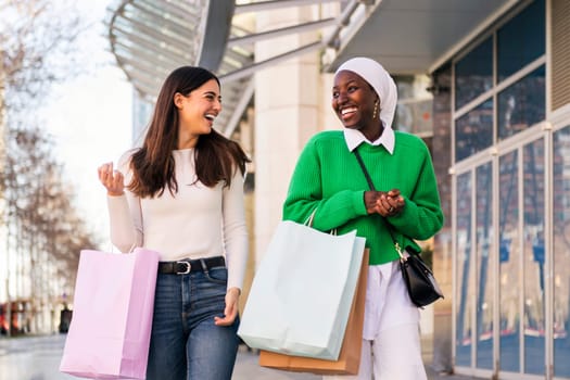 multiracial couple of female friends smiling happy walking in a shopping area, friendship and modern lifestyle concept