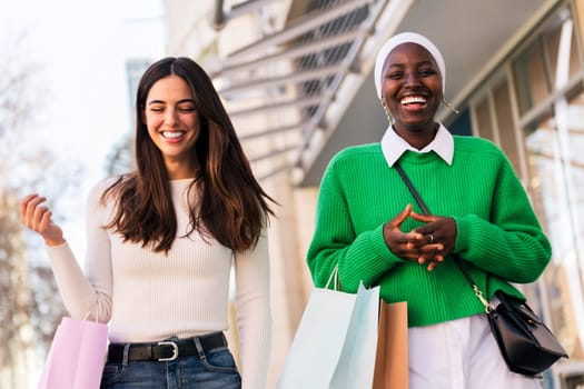 two black and white women smiling happy walking in a shopping area, friendship and modern lifestyle concept