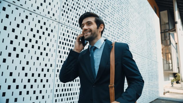 Smart business man using phone to talking about business investment. Happy manager walking at street while talking on smart phone to discuss business plan or marketing strategy or working. Exultant.