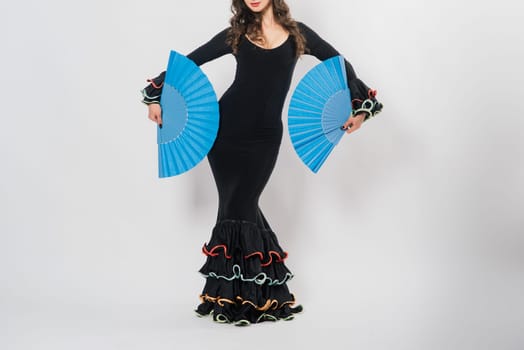 Portrait of beautiful young woman dancing flamenco with fan in studio