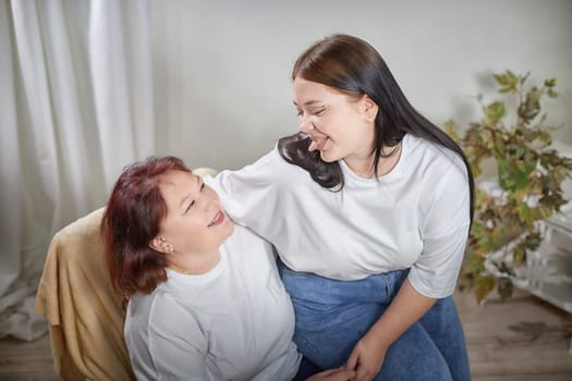 Happy Overweight family with mother and daughter in room. Middle aged woman and teenager girl having fun, joy and hugging