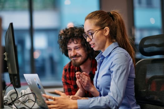 Business colleagues, a man and a woman, engage in discussing business strategies while attentively gazing at a computer monitor, epitomizing collaboration and innovation.