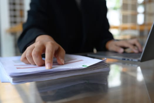 Financial analyst using laptop and checking data report at his office desk.