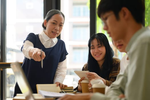 Senior professor explaining something to students during class at university.