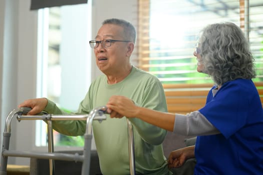 Nurse assisting elderly man using walking frame. Rehabilitation and Healthcare concept.